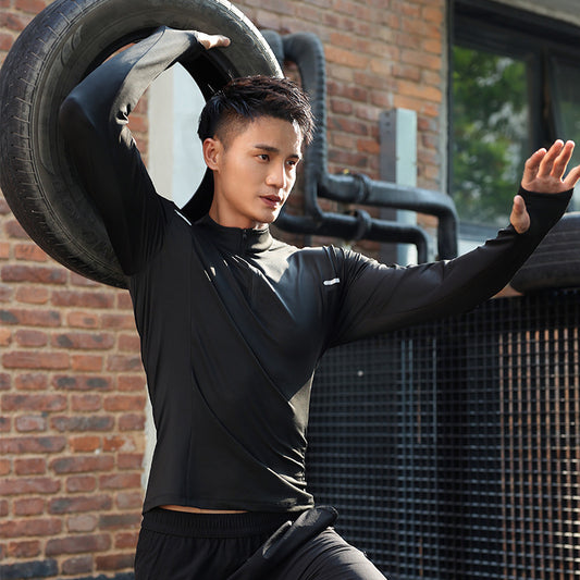 Person lifting a tire in an outdoor setting with a brick wall and metal fence.